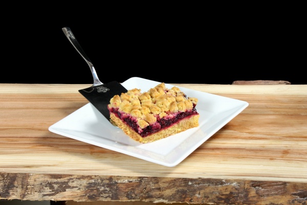 Cuadros de bizcocho casero con compota de cerezas (55%) y delicioso crujiente de crumble de mantequilla.